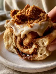 A macro photo of an oversized Biscoff cinnamon roll being pulled apart, revealing airy pockets and a dark Biscoff swirl. (Biscoff Cinnamon Rolls)