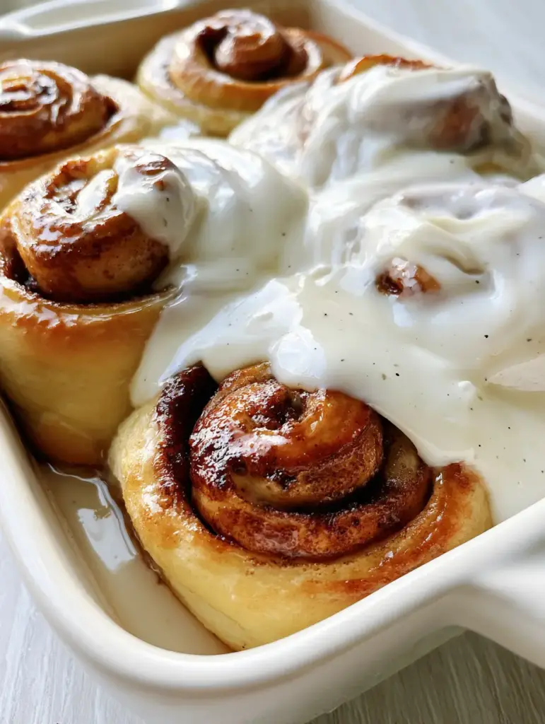 Extreme top-down view of fluffy cinnamon rolls with dark caramelized swirls and glossy white icing. (cinnamon rolls recipe)