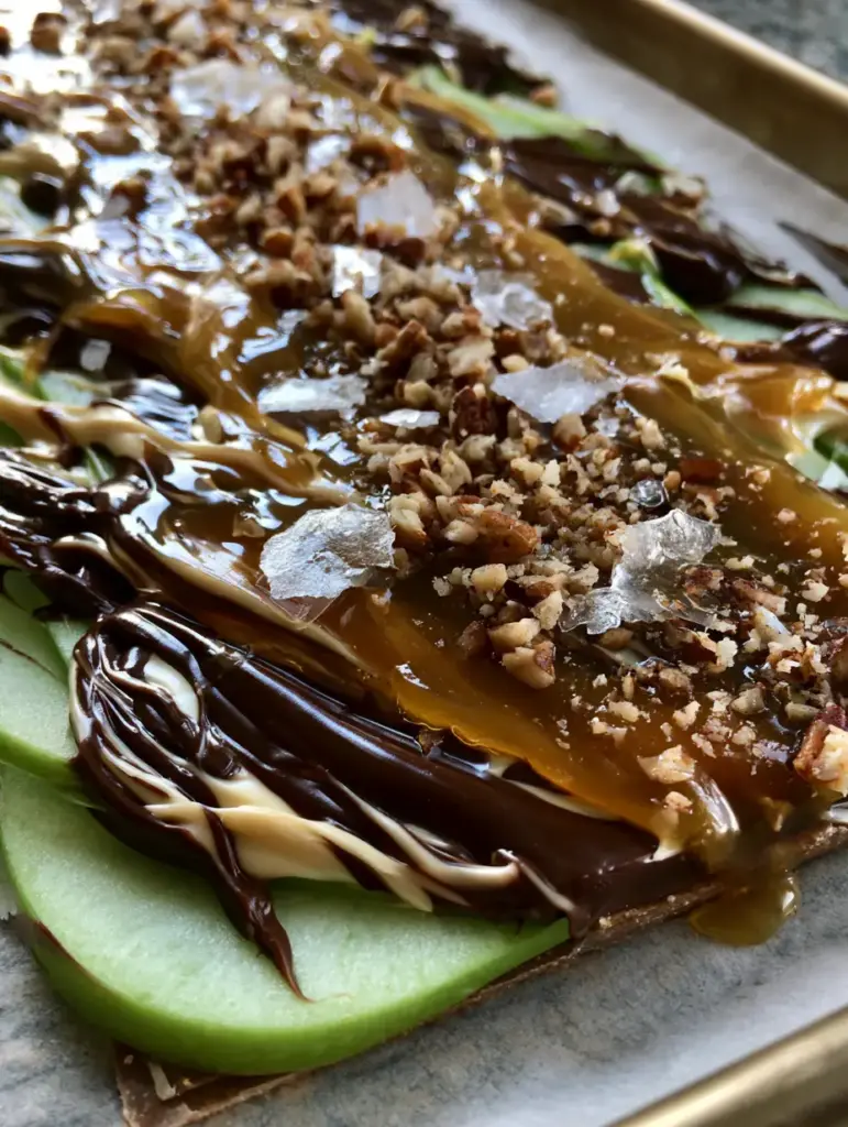 Caramel Apple Bark with Salted Dark Chocolate and Toasted Pecans 2 A handheld smartphone photo of Caramel Apple Bark in natural light on a high-end kitchen counter. (caramel apple bark)