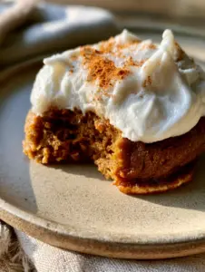 Extreme macro close-up of a thick chewy pumpkin cookie with a bite taken out showing a dense fudgy interior. (frosted pumpkin cookies)