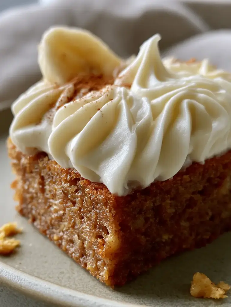 Banana Bars with Thick Swirled Cream Cheese Frosting 1 Top-down macro view of banana bars featuring fresh banana slice garnish and fine cinnamon powder dusting.