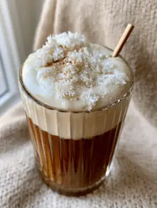 Close up of a Vanilla Almond Snowflake Latte showing the dark espresso base and thick 2-inch glossy almond milk foam.