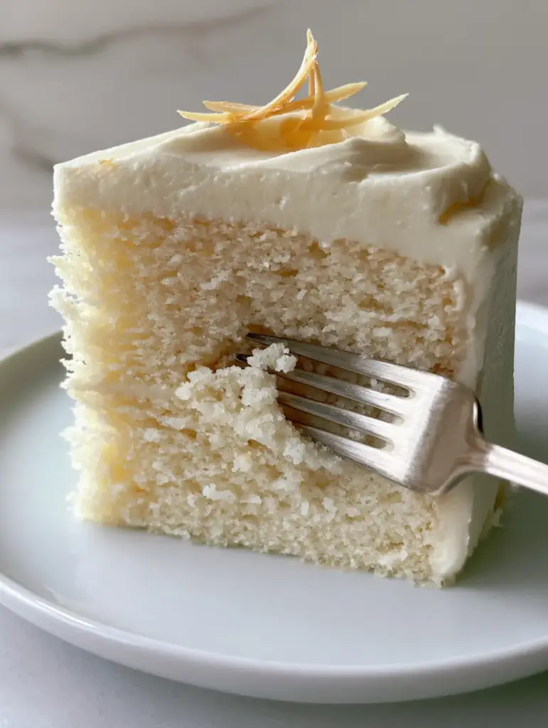 Macro close-up of White Almond Cake showing the velvety interior crumb and a silver fork.